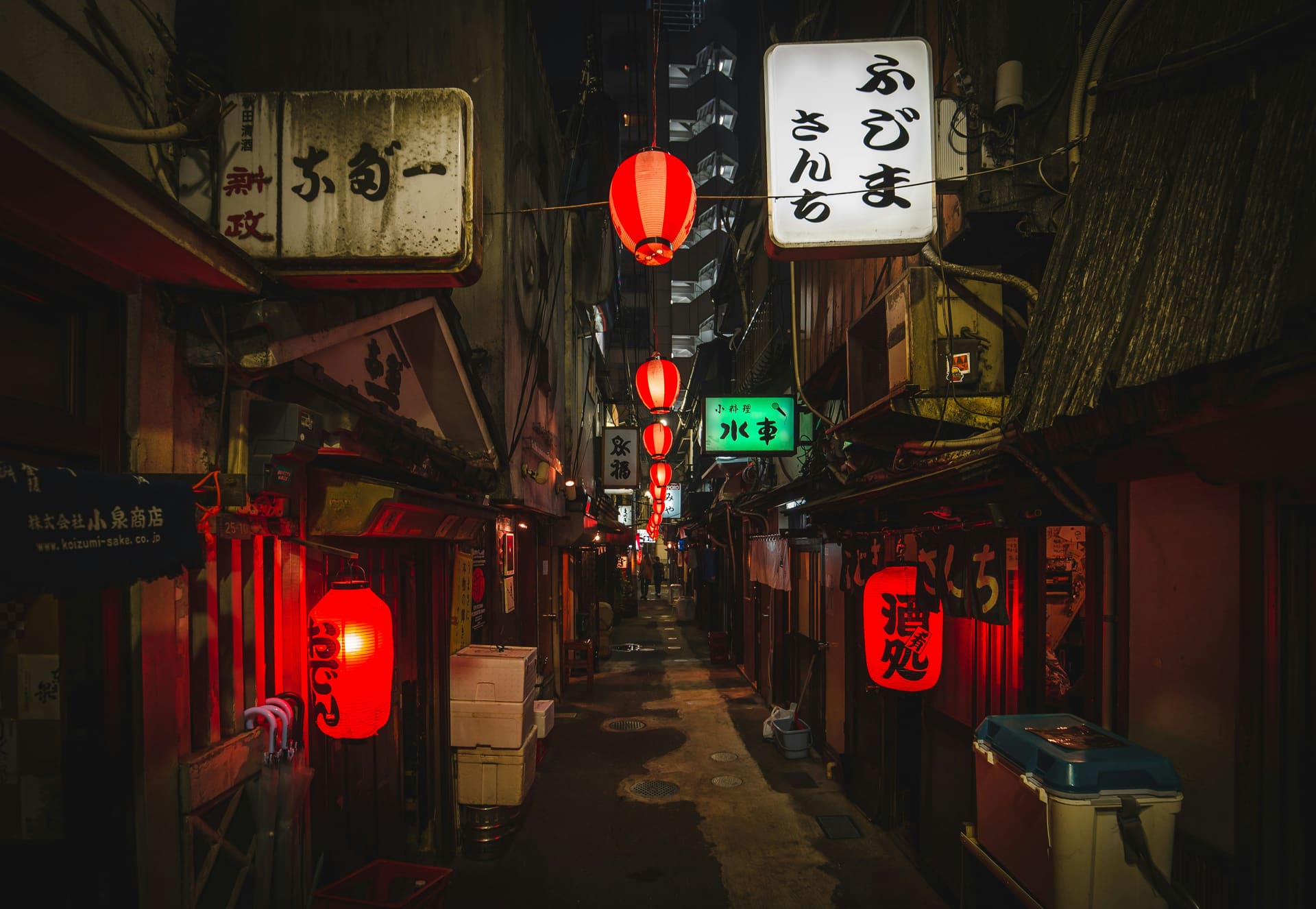 A narrow Japanese alley at night lit by red paper lanterns and shop signs