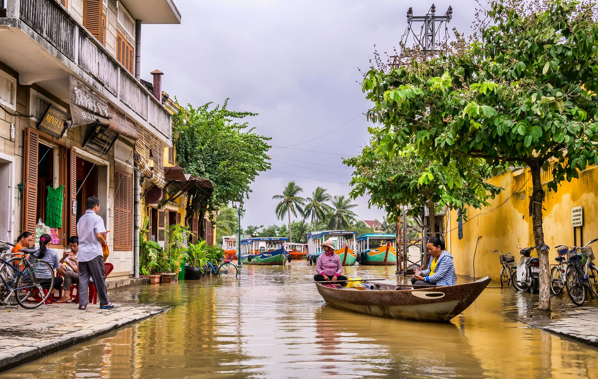 Wooden boats on a flooded street between old town shopfronts in Hoi An